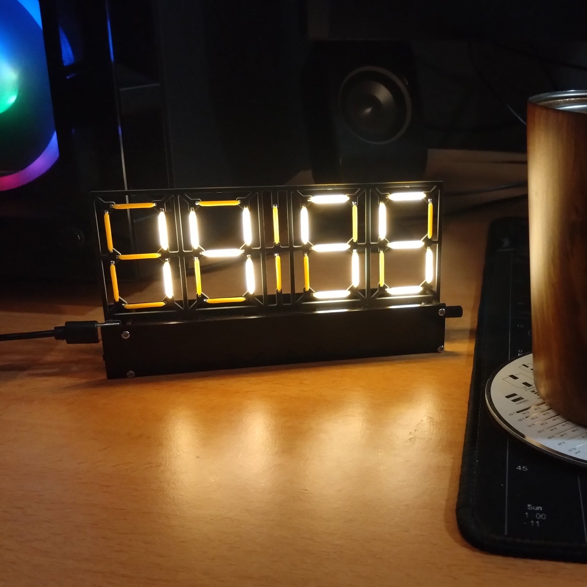 Desk setup with a cup, digital clock, and RGB lighting