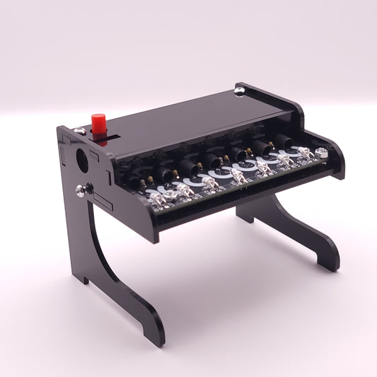 Small black piano-like instrument with LEDs on a white background