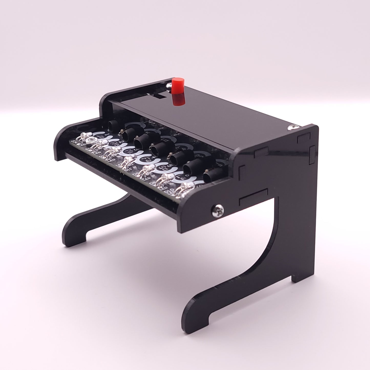 Small black piano-like instrument with LEDs on a white background