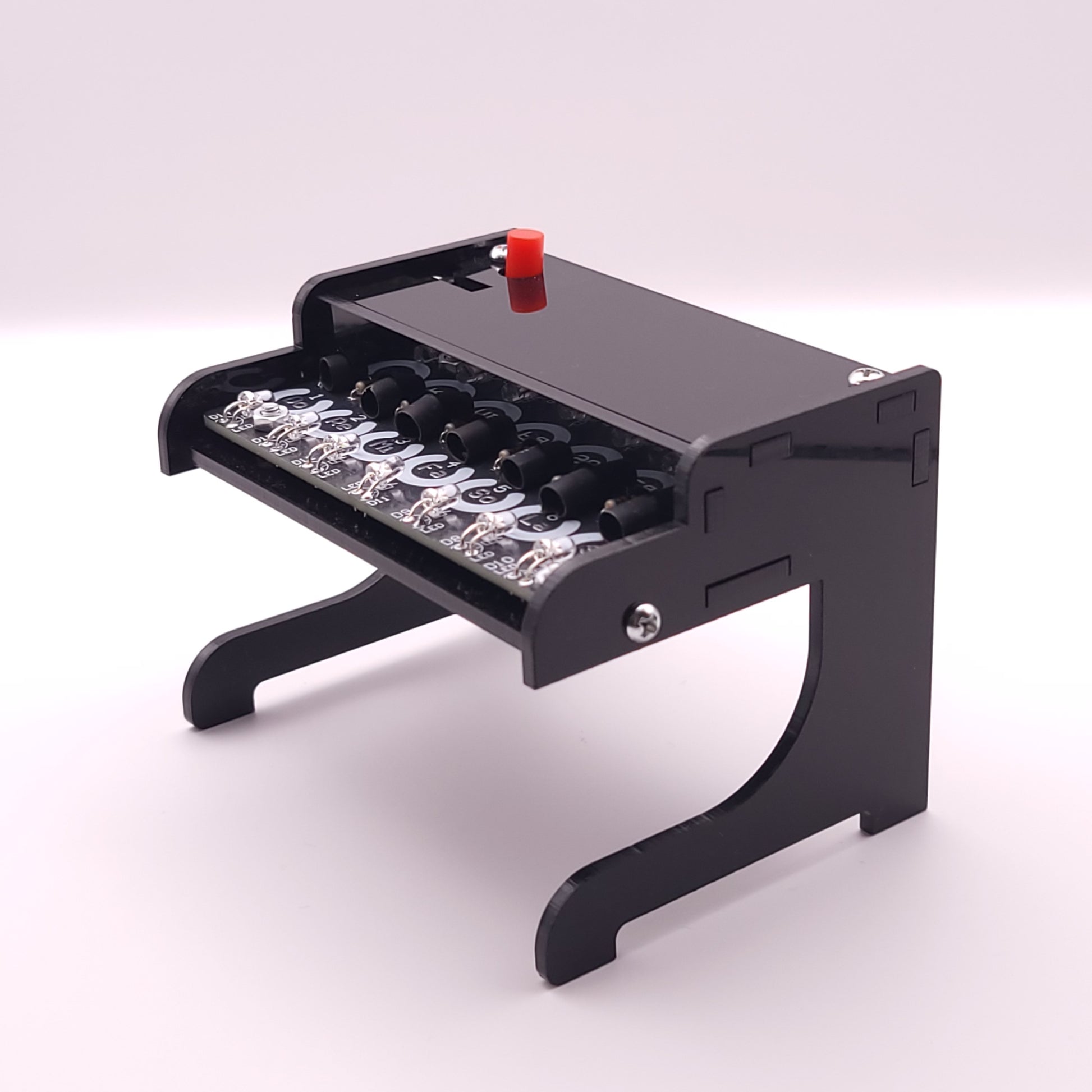 Small black piano-like instrument with LEDs on a white background